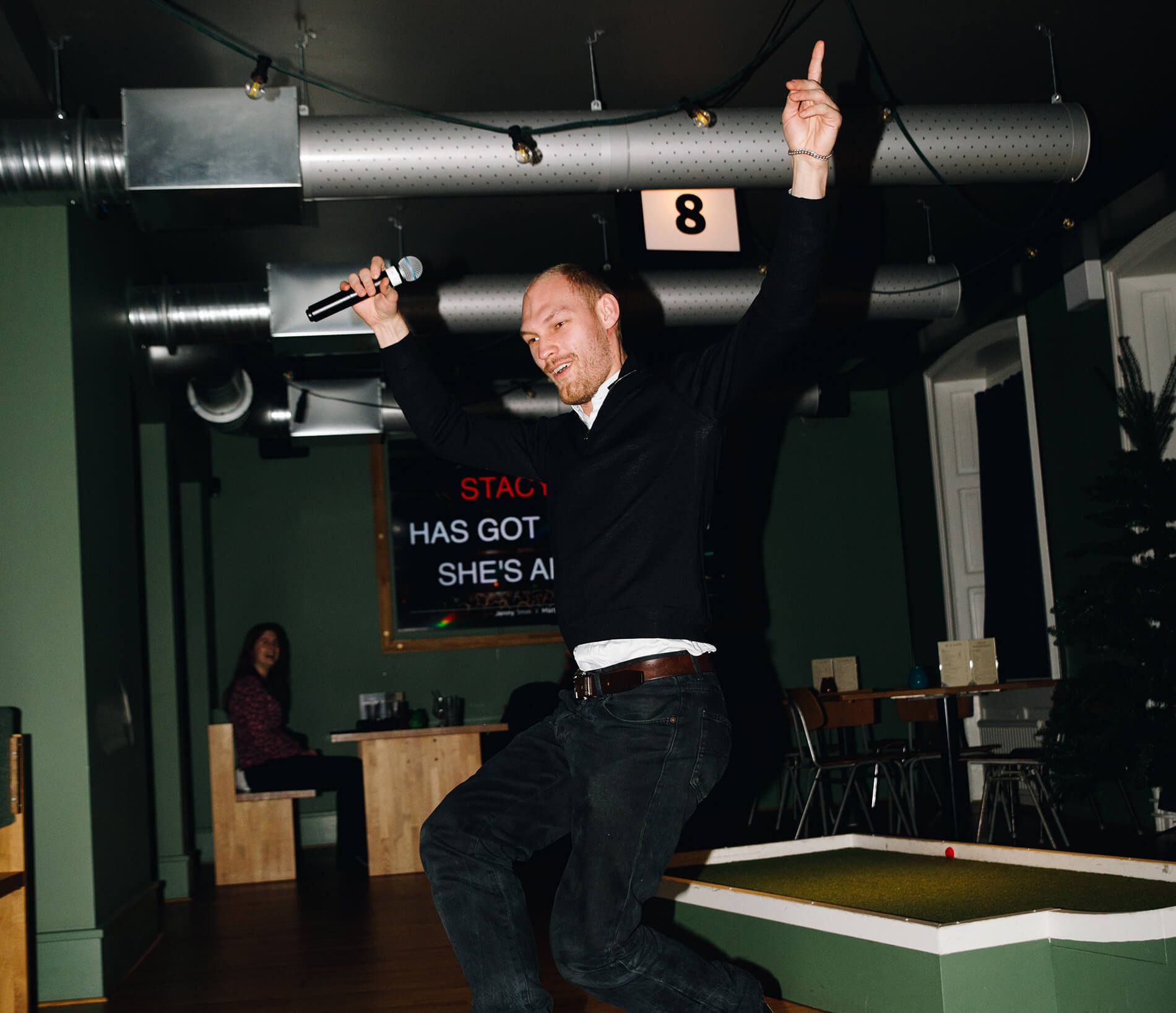 En glad person som dansar medan han sjunger karaoke i Malmö på Camping Bar vid Stortorget.